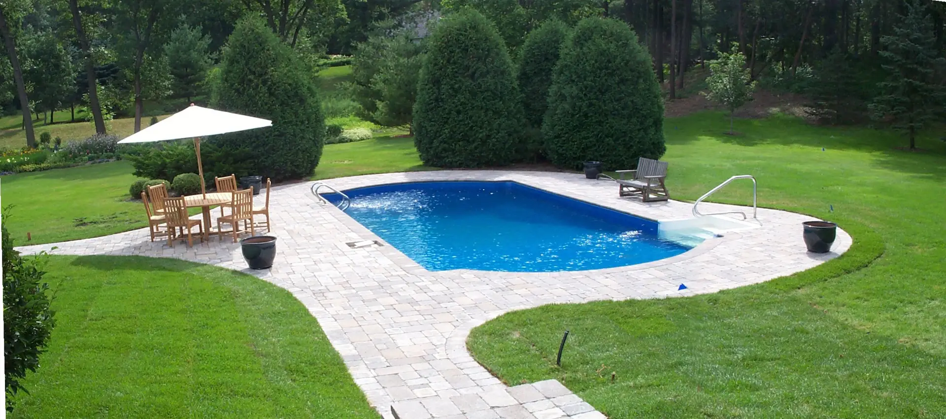 a swimming pool with a lawn and trees